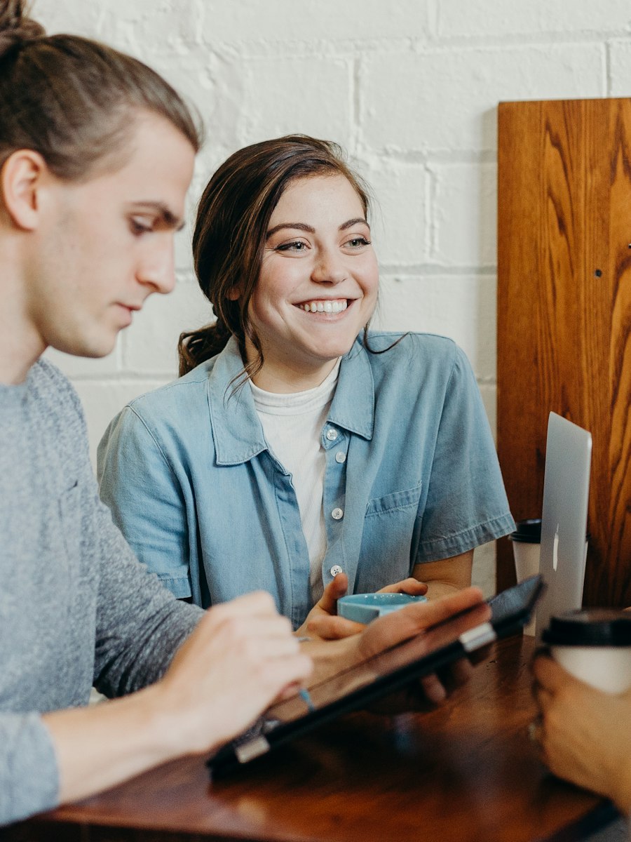 Four colleagues reviewing a tablet together and smiling